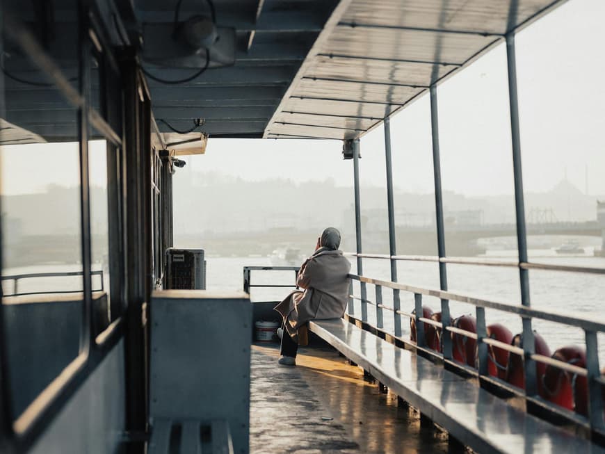 Alleine reisen als Frau kann eine Herausforderung sein. Frau sitzt auf einem Schiff und guckt aufs Wasser.