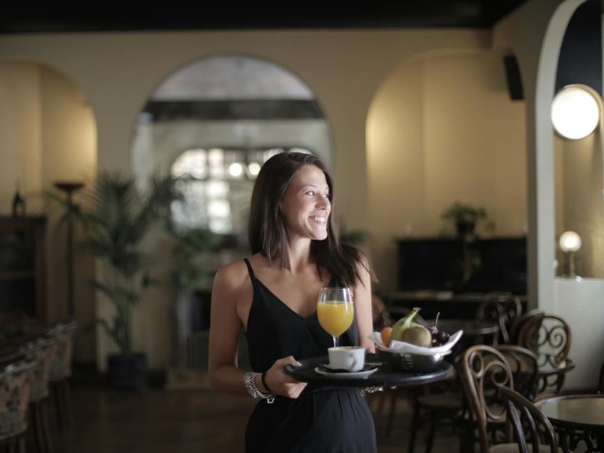 Diät Hotels können beim Abnehmen helfen. Frau mit einem Tablett und einem Glas Orangensaft und Obst.