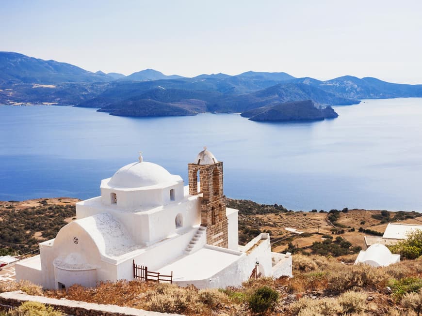 Eine griechische Kapelle mit dem Meer und Landschaft im Hintergrund.