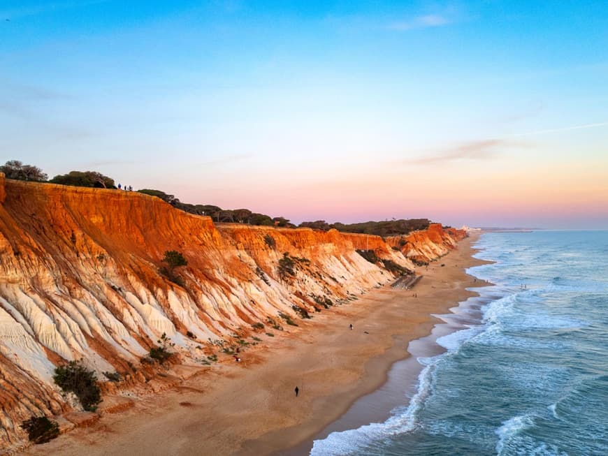 Rötliche Klippen und blaues Meer an der Praia da Falésia in Portugal.