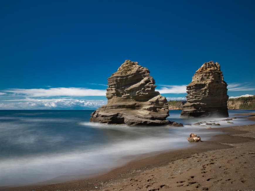 Zwei große Felsen, die am Strand von Procida im Meer stehen.