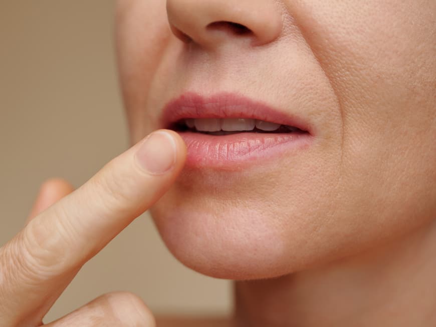 Frau cremt Lippen ein