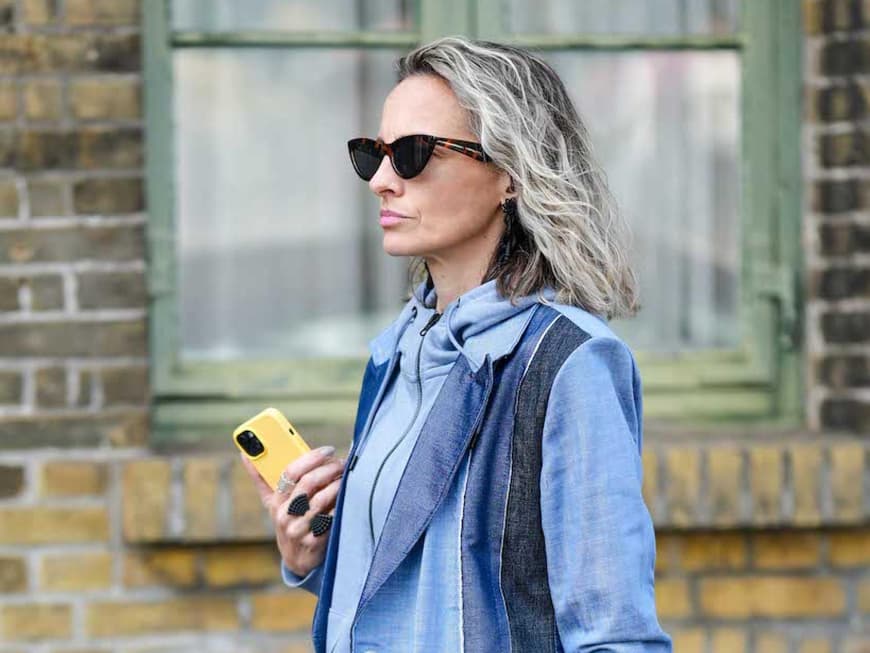 Ältere Frauen mit grauen Haaren, Sonnenbrille und einem Jeansmantel.