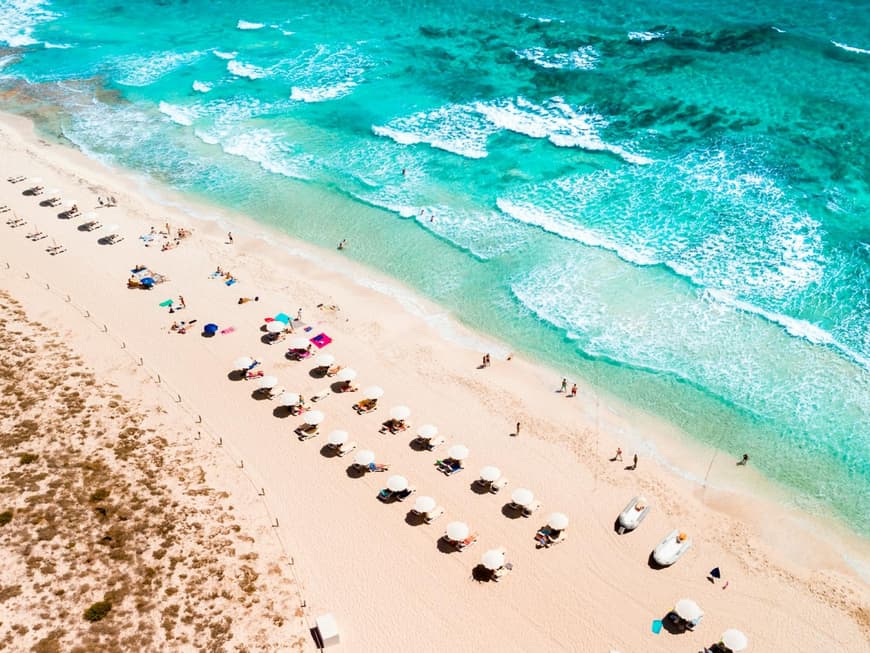 Der Strand von Formentera mit Liegen, Sonnenschirmen und Menschen.