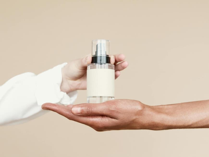 Parfum für Frauen ab 40 sollte eine gewisse Reife versprühen. Eine Hand stellt ein Parfum in eine andere Hand.