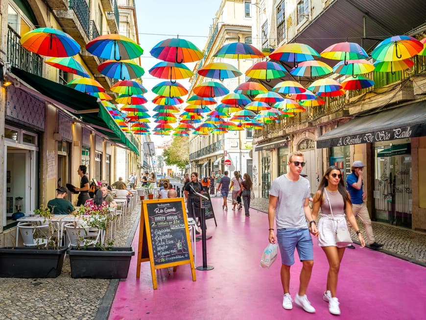 Eine pinke Straße mit bunten Regenschirmen in der Luft.