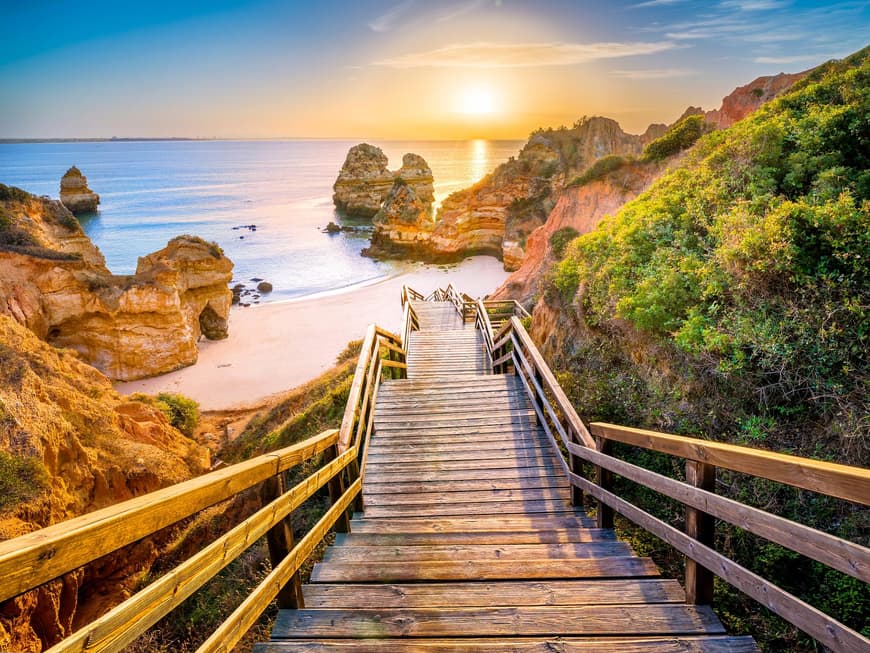 Ein Blick auf den Sonnenaufgang am Camilo Beach mit einer Holztreppe, Sand und Felsen.