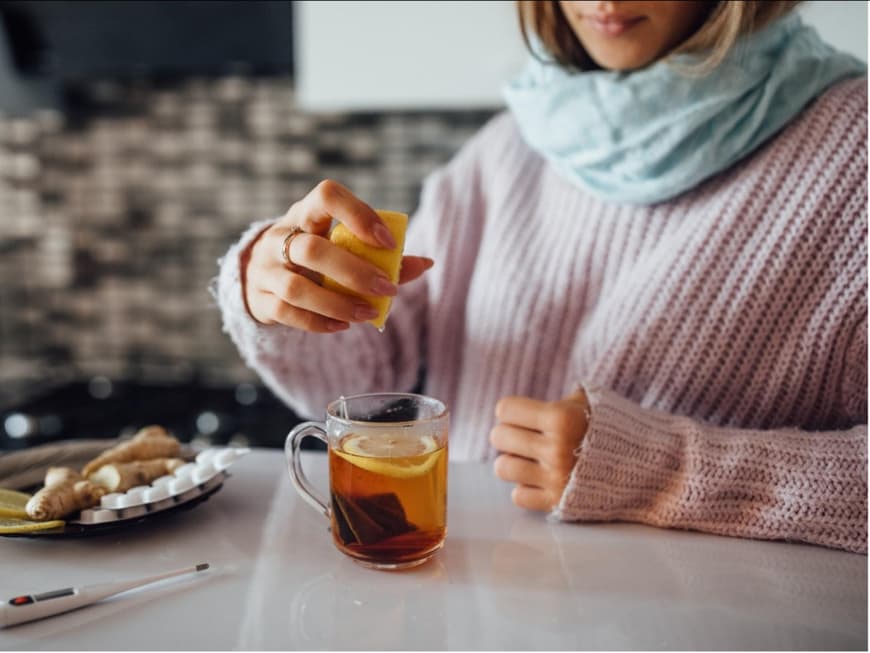 Eine Frau presst eine Zitrone in eine Tasse Tee