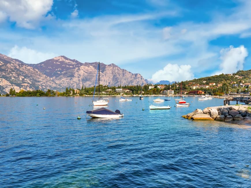 Der Gardasee mit Booten auf dem Wasser und Bergen im Hintergrund.