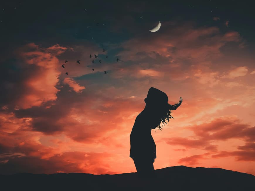 Frau steht unter dem Abendhimmel mit Mond
