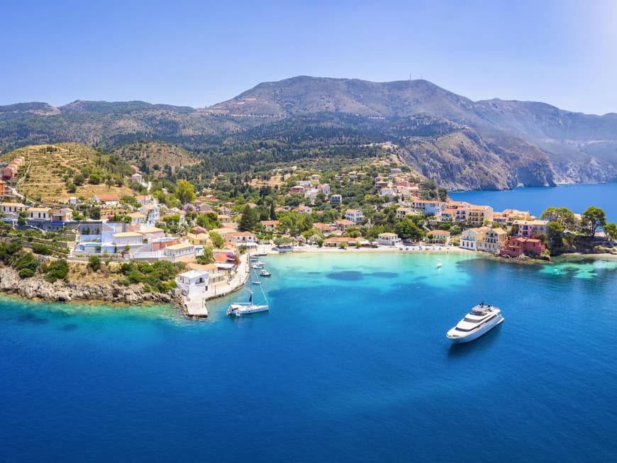 Welche griechische Insel die schönste ist, hängt von deinen persönlichen Vorlieben ab. Luftaufnahme einer griechischen Insel mit Häusern auf dem Festland und Booten im Wasser.