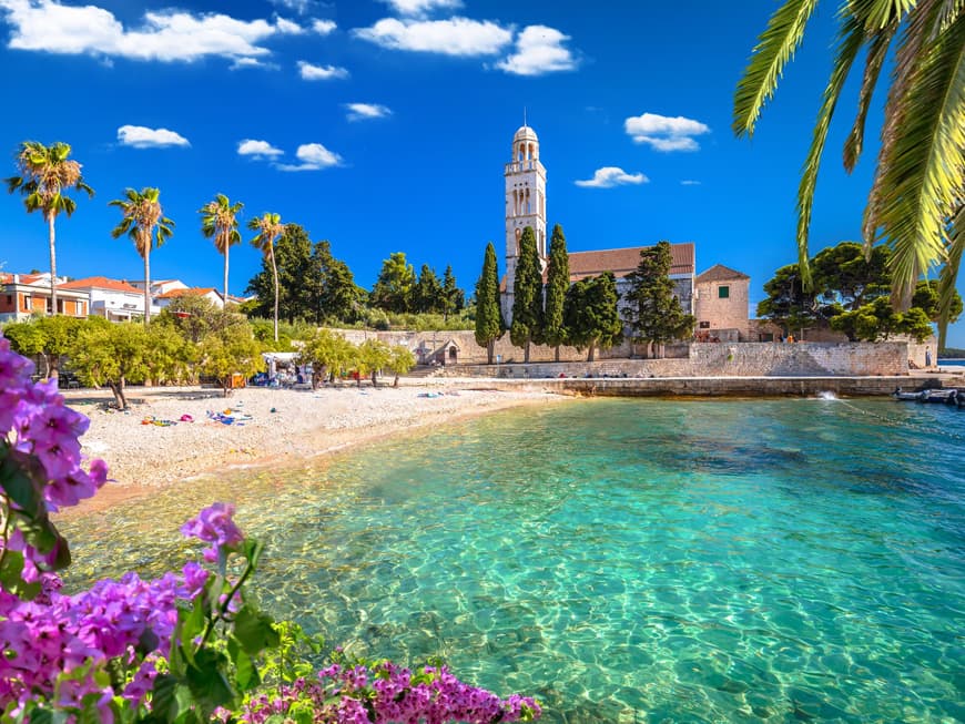 Strand mit ein paar Handtüchern, Palmen und einer Kirche im Hintergrund