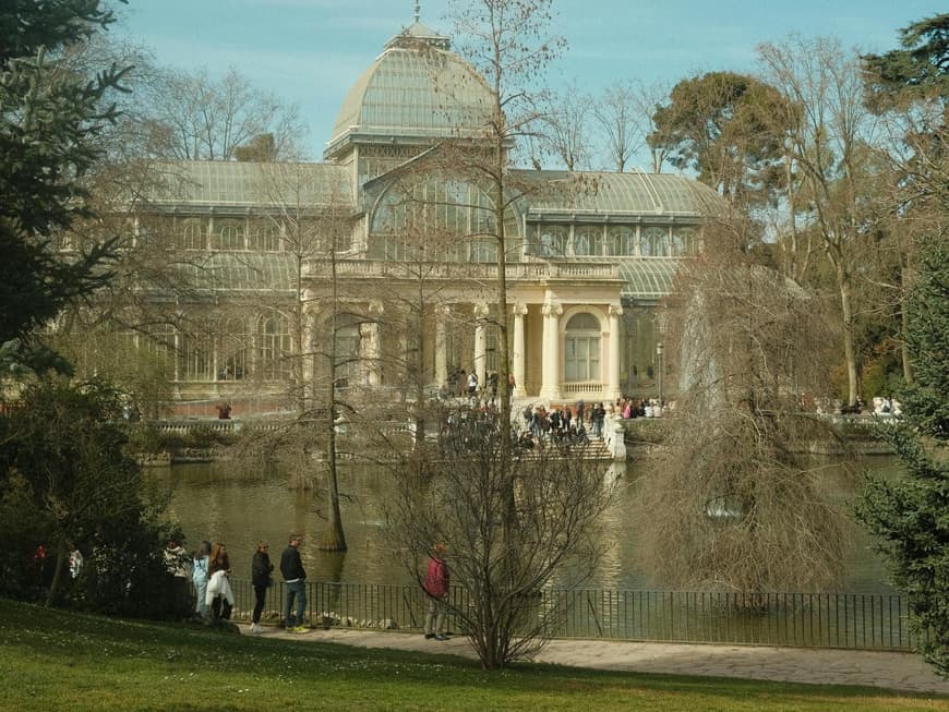 Ein Blick auf ein altes Gebäude in einem Park mit vielen Menschen davor.