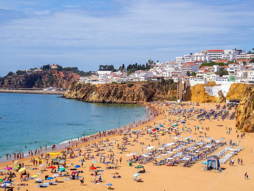 Der Praia dos Pescadores zieht viele Besucher an. Ein Strand mit vielen Menschen und einer Küste voller heller Häuser.