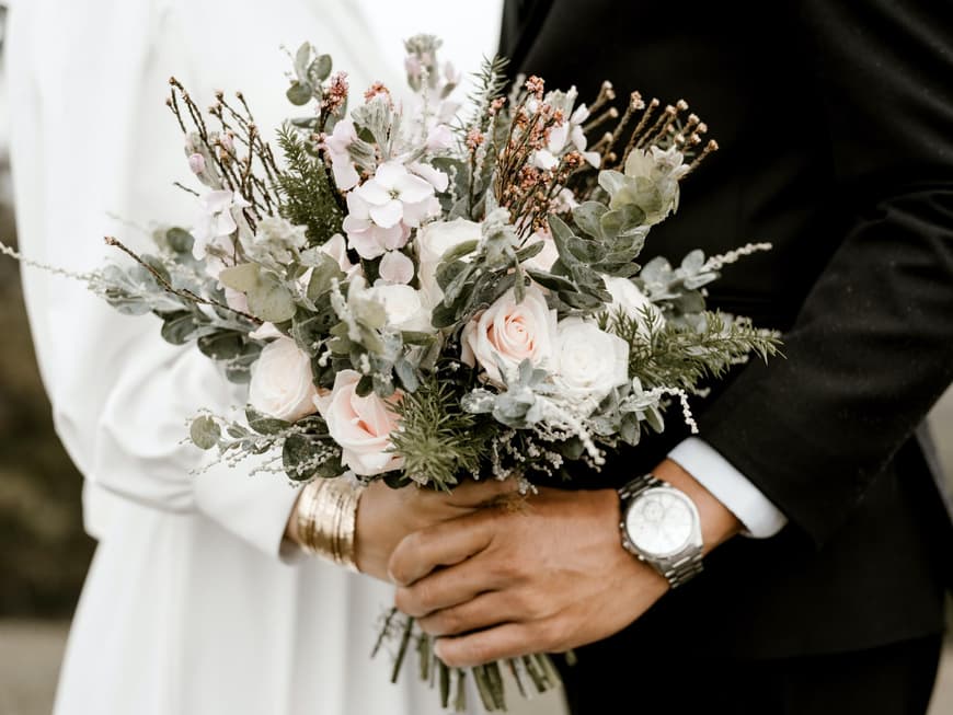 Ein Hochzeitspaar hält gemeinsam den Brautstrauß