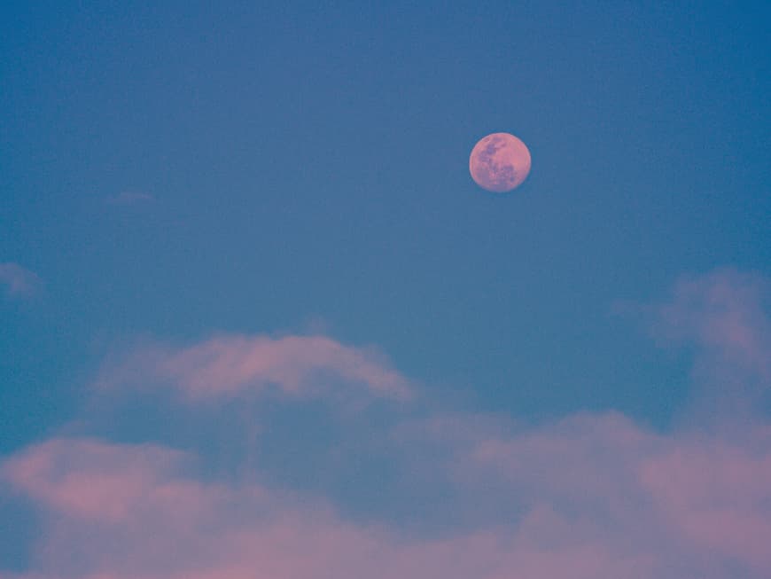 Blauer Himmel mit rosa Mond und rosa Wolken