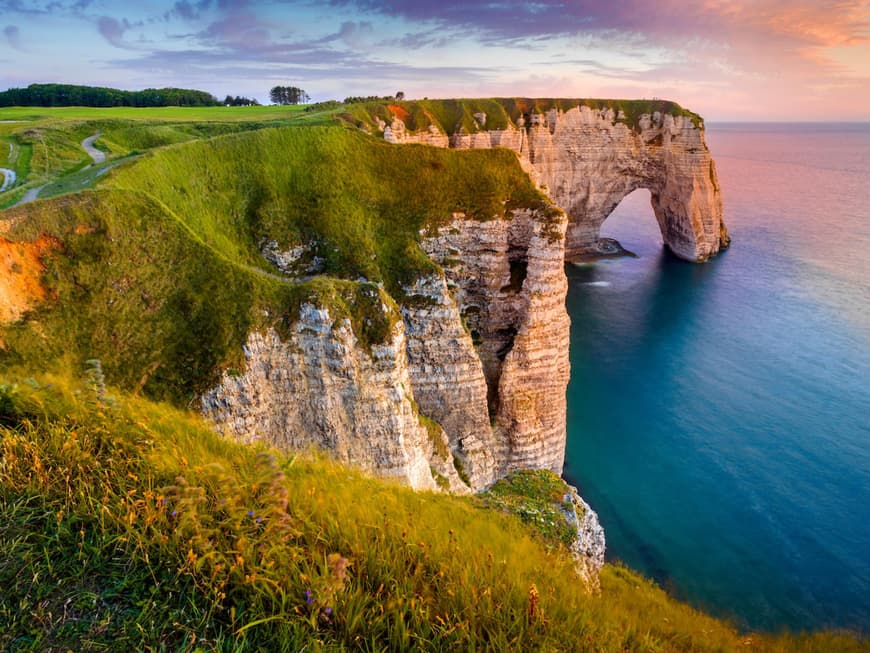 Etretat ist ein echtes Naturschauspiel. Ein Blick auf Felsen und Klippen mit Gras darauf und einem schönen Himmel im Hintergrund.