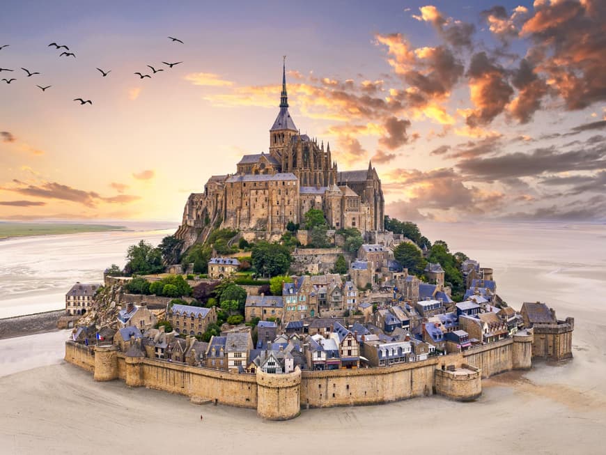 Der Mont Saint Michel sieht einfach atemberaubend aus. Ein Blick auf den Mont Saint Michel bei Sonnenaufgang mit Wolken und Vögeln am Himmel.