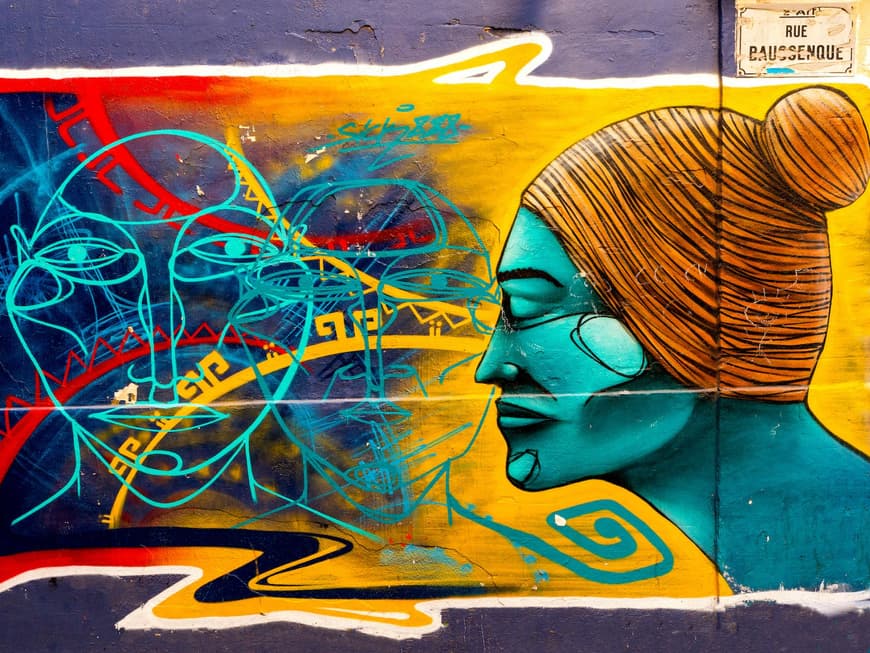 Street Art ist in Le Panier gängig. Bunte Street Art an einer Wand, auf der ein türkisfarbener Kopf von der Seite mit weiteren Umrissen und Linien zu sehen ist.