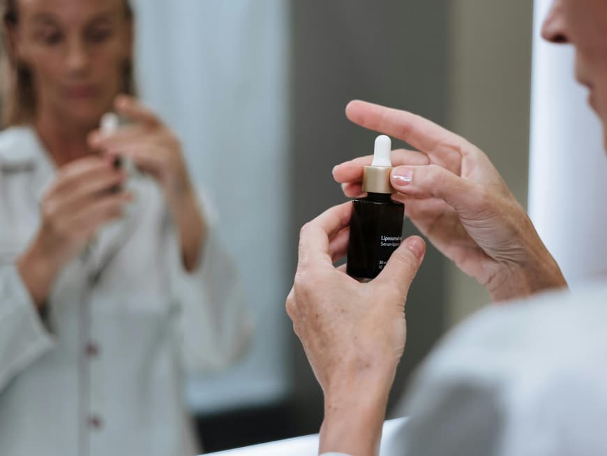 Frau hält Hautpflegeserum in der Hand.