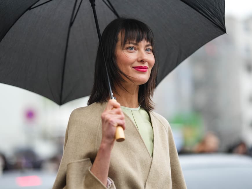 Wie bleibt unsere Frisur trotz Wind und Wetter frisch? Das verraten uns jetzt Haar-Stylisten! Frau mit Regenschirm