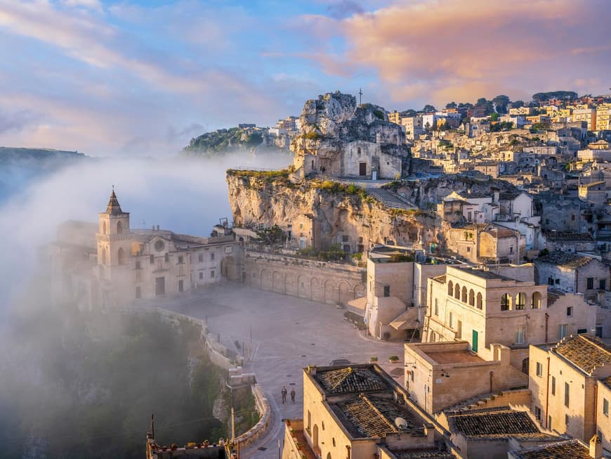 Matera sieht im Morgennebel richtig mystisch aus. Ein Blick auf Matera mit vielen beigefarbenen Häusern und Nebel drum herum.