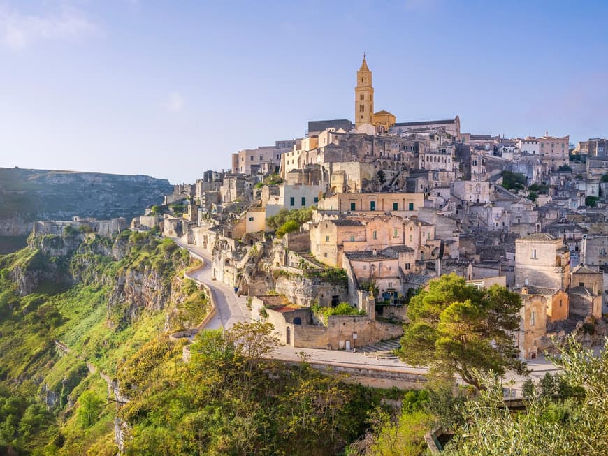 Matera hat eine schöne alte Kathedrale zu bieten. Ein Blick auf viele alte Häuser auf einem Hügel mit einer Kathedrale ganz oben.