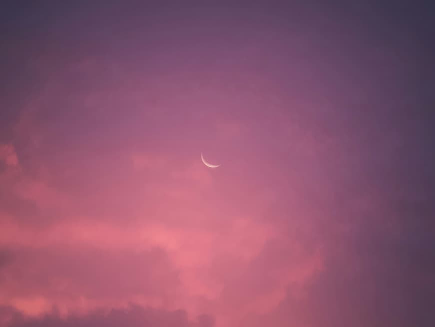 Welche 4 Sternzeichen im Dezember eine große Portion Glück erwartet? Das erfährst du hier. Rosa Wolkenhimmel mit Sichelmond