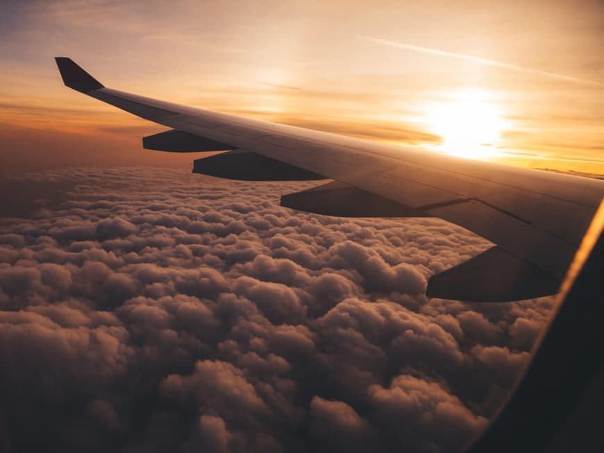 Ein Flugzeug fliegt Richtung Sonnenaufgang