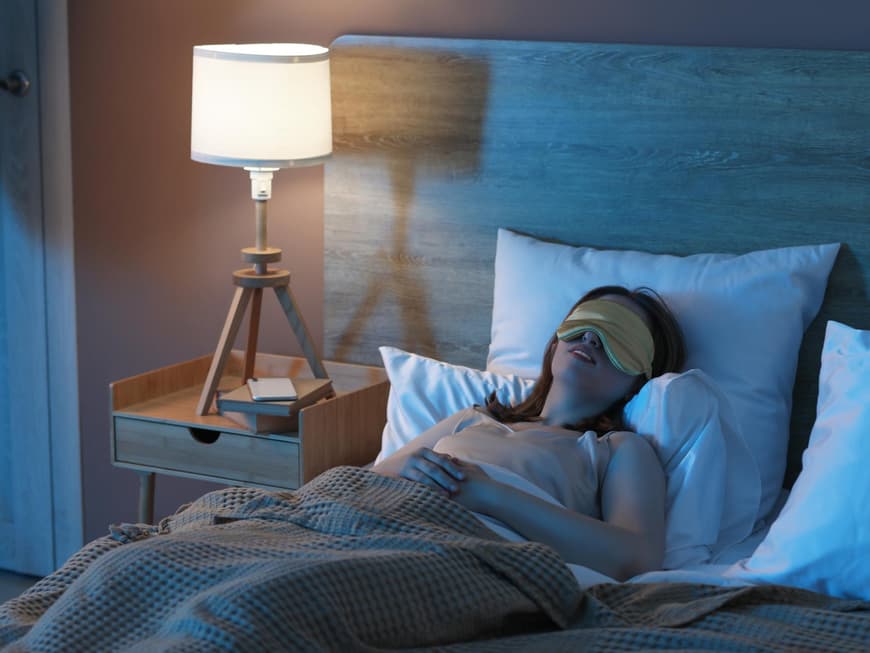 Frau schläft im Bett mit Schlafmaske