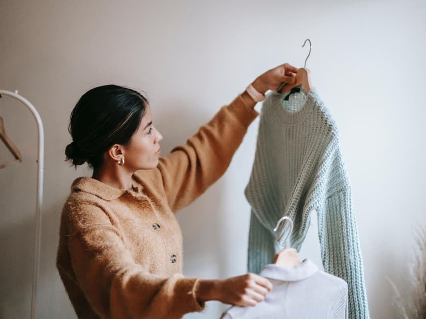 Eine junge Frau sortiert Kleidung aus