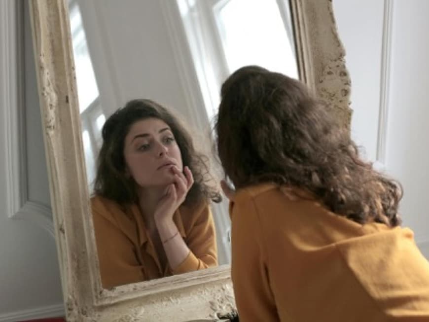 Eine Frau betrachtet sich im Spiegel