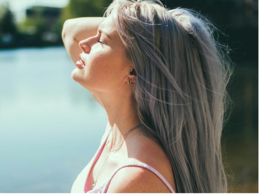 Eine Frau hält ihr Gesicht in die Sonne