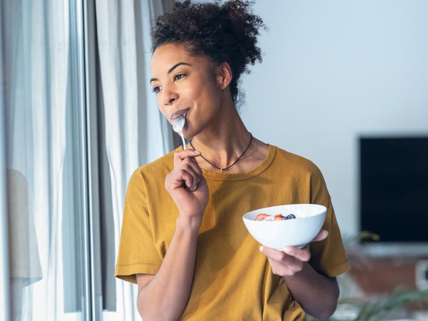 Eine Frau isst einen Joghurt mit Früchten