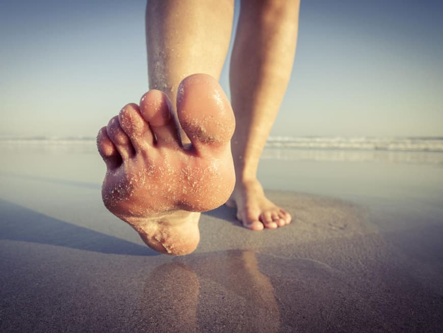 Frau barfuß am Strand