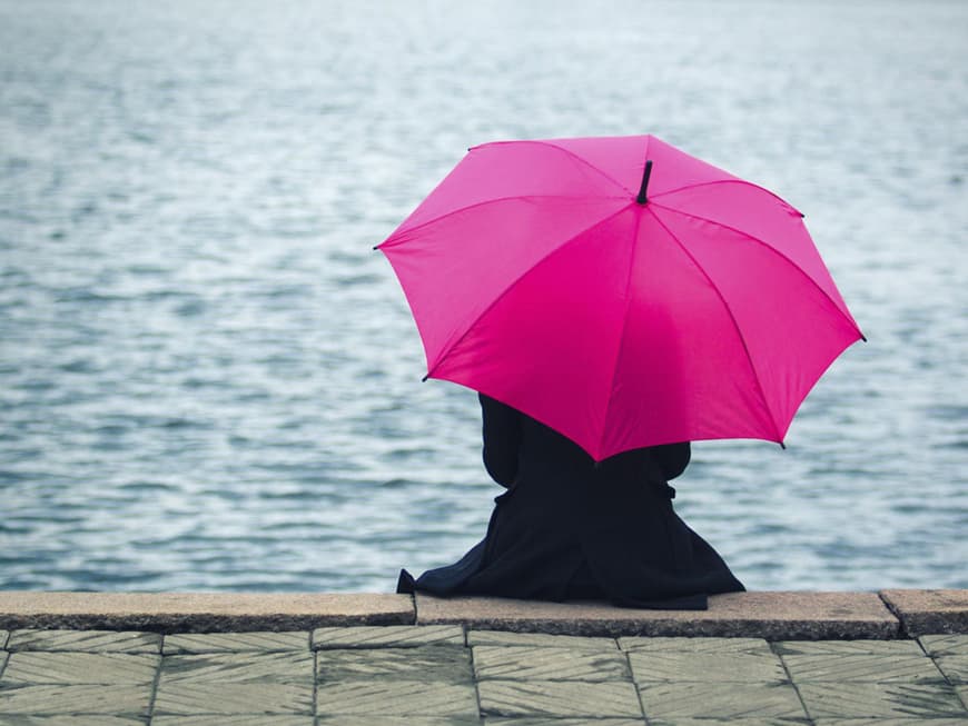 Frau mit Regenschirm am See
