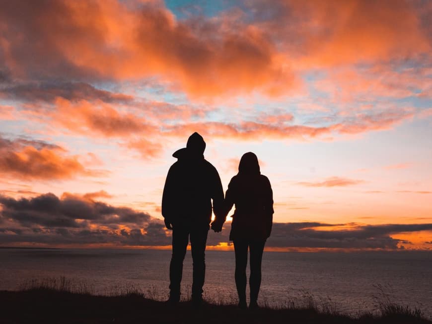 Mit seinem Partner teilt man gern schöne Momente. Frau und Mann von hinten schauen sich den Sonnenuntergang an.